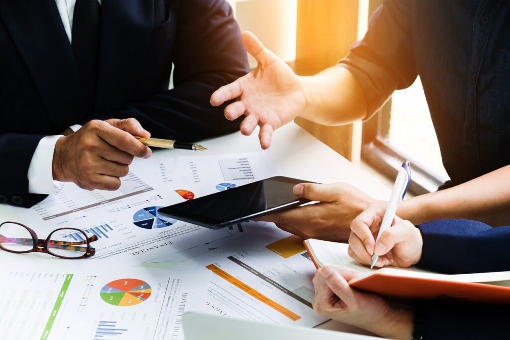 Profissionais analisando gráficos financeiros impressos sobre uma mesa de reunião