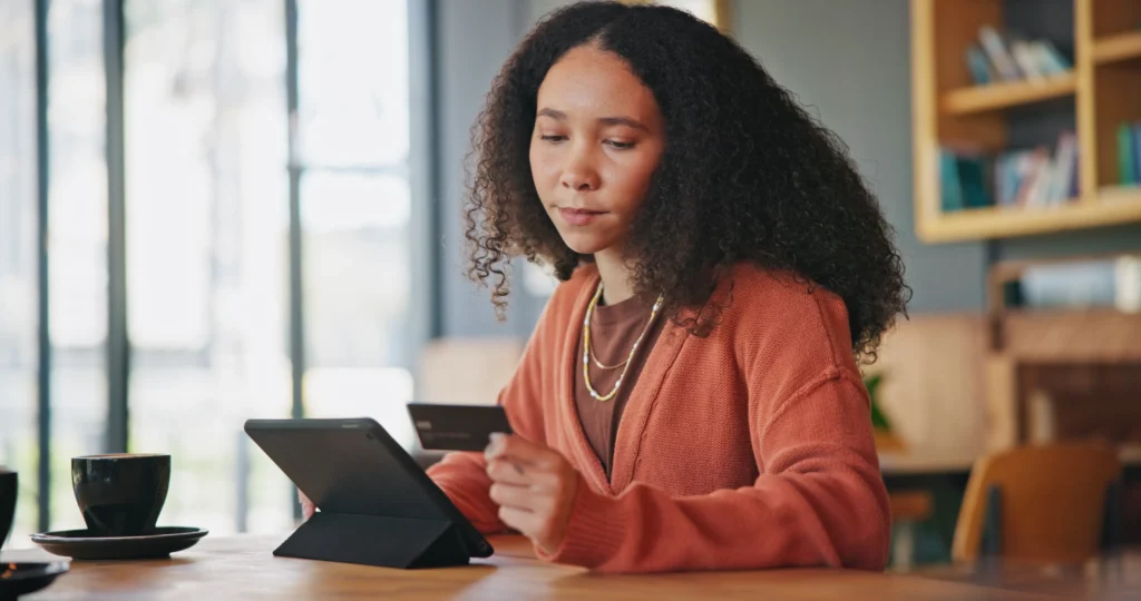 Mulher usando um tablet e um cartão para fazer um pagamento digital